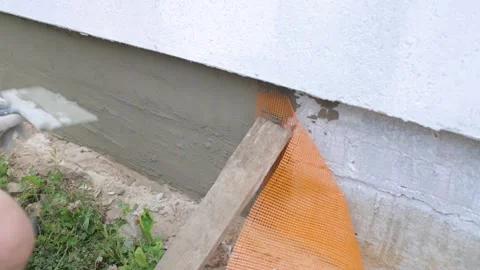 Applying and leveling cement plaster to the foundation of the house. 库存影片 250933767
