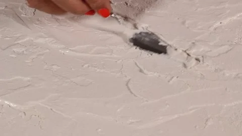 Applying an artistic white textured plaster with a small metal palette knife Stock Footage 135751608
