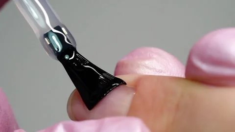 Applying a base gel polish with a brush by a manicure master. Several shots. Stock Footage 220729558