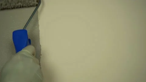 Applying beige paint with a roller brush to the wall. Close up Stock Footage 219746096