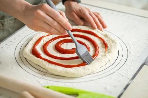 Applying berry jam to dessert roll dough with a kitchen brush Stock Photos