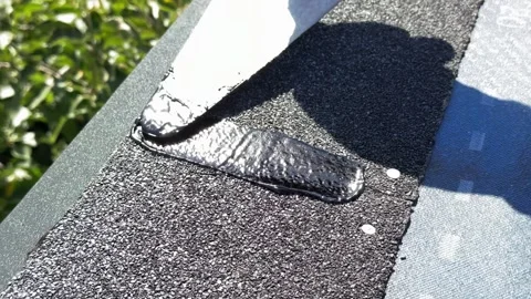 Applying bitumen mastic to roofing shingle seams Stock Footage 346718970
