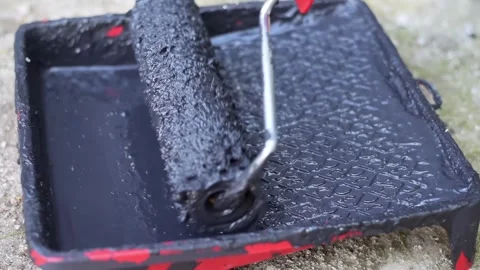 Applying black liquid paint to a textured roller in a red plastic tray outd.. Stock Footage 339344658