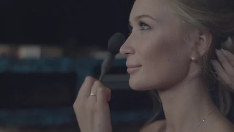 Applying blush makeup with brush to cheekbones of young woman close slow motion Stock Footage 72597373