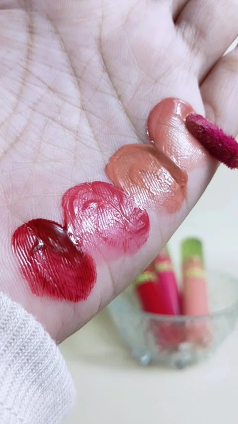 Applying bright red lip stain to palm skin using a makeup brush applicator... Stock Footage 338318660