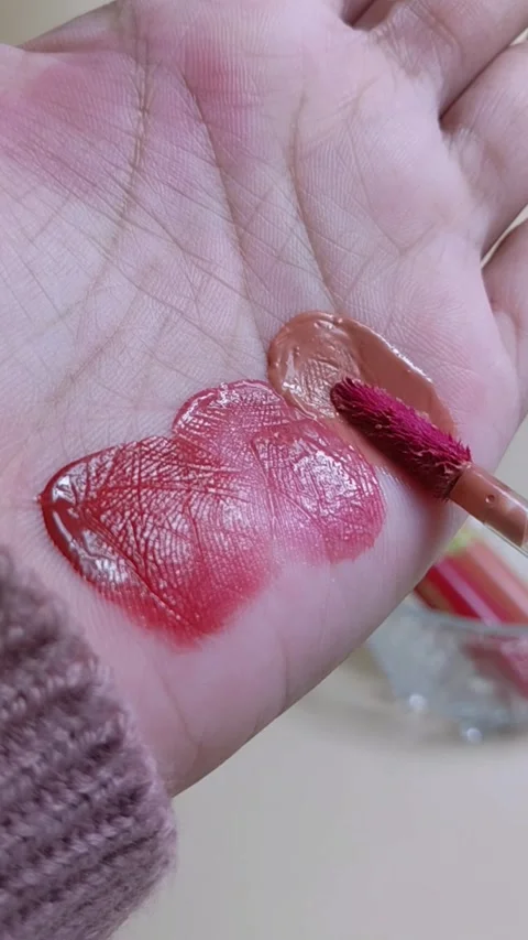 Applying brownish red lip tint on palm using makeup brush applicator. Stock Footage 338401827