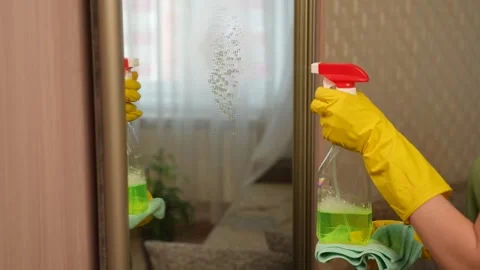 Applying cleaning solution to a mirror in the house using a spray bottle. Using Video stock 311051489