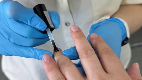 Applying clear nail polish to natural nails of an adult woman during a Stock Footage 345172994