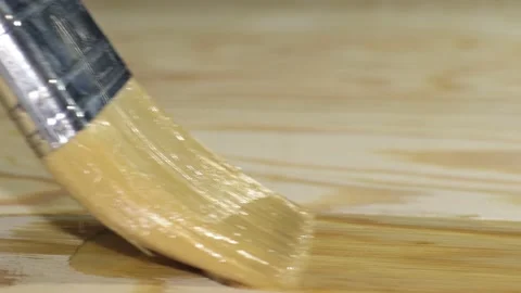Applying clear paint to a wood surface with a brush Stock Footage 217433576