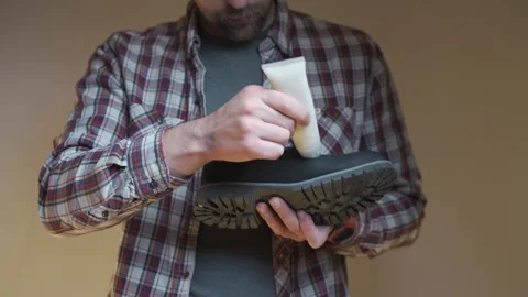 Applying conditioner to a leather boot, the person focuses on cleaning and Stock Footage 334212809