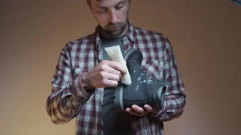 Applying conditioner to a leather boot, the person focuses on cleaning and Video stock 334213102