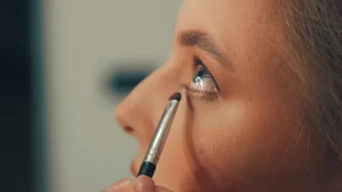 Applying cosmetics to achieve a smooth, glowing complexion for a Slavic girl Stock Footage 309049936