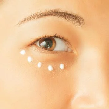 Applying cream for skin around eye Stock Photos