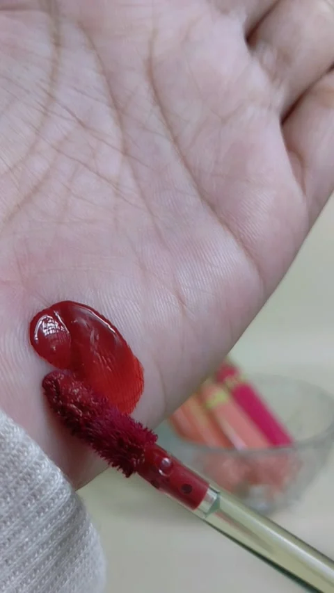 Applying dark red lip tint to hand skin using makeup brush. Vertical close .. Stock Footage 338318668