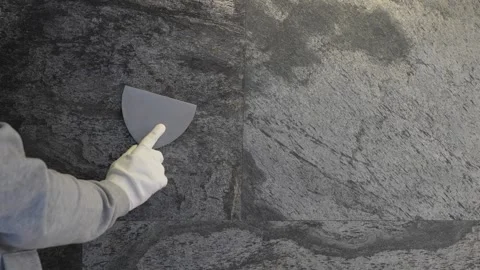 Applying decorative plaster on wall by a steel trowel. Stock Footage 258470824