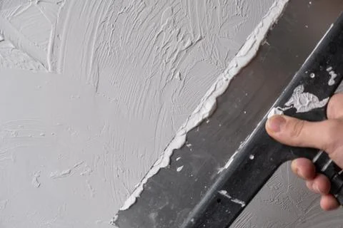 Applying decorative putty. White abstract texture of surface covered with put Stock Photos