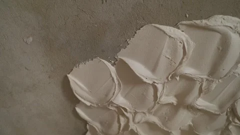 Applying decorative white plaster on a grey concrete wall in a textured pattern Stock Footage 347910258