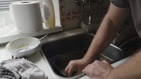 Applying Detergent to Remove Burnt Cooking Residue from Oven Tray in Sink Stock Footage 340875626