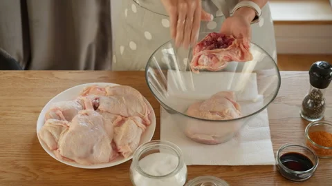 Applying a dry rub of salt and spices to raw, skin-on chicken thighs Stock Footage 315357392