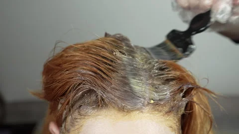 Applying dye to the regrown roots of red hair. Stock Footage 274469902