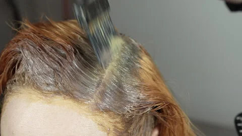 Applying dye to the regrown roots of red hair. Stock Footage 274831642