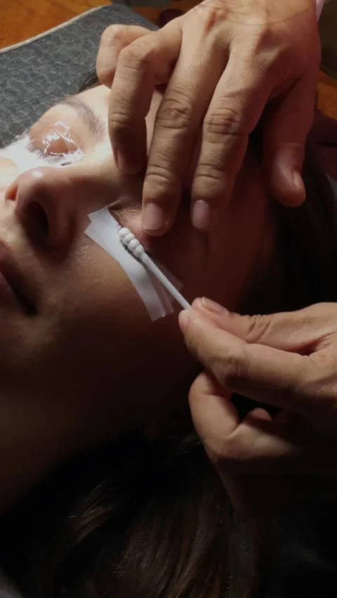 Applying eyelash extensions on a woman's eye during a beauty treatment procedure Stock Footage 332833821