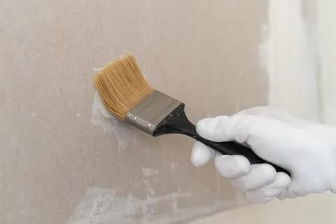 Applying finish coat with precision brush on drywall surface in renovation Fotos Stock