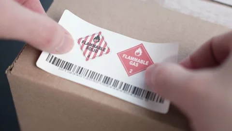 Applying a Flammable Warning Danger Label on a Shipping Box Stock Footage 185112532