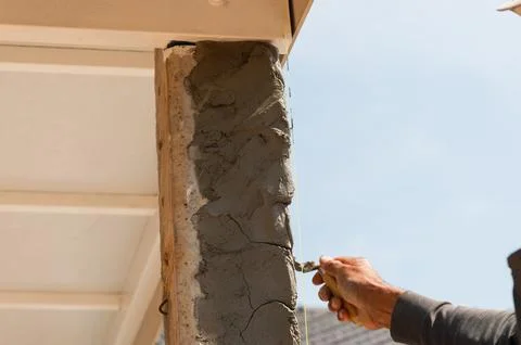 Applying fresh cement to a pillar at construction site outdoor work hands- .. Foto stock