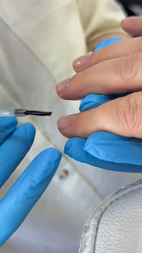 Applying gel nail polish during professional manicure, nail technician coating Stock Footage 345182112