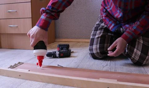 Applying glue to a part of a bed during furniture assembly Stock Photos