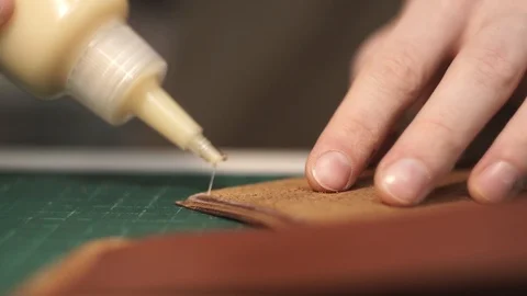 Applying glue to the skin blank. Close-up. Brown patches of leather. Purse Stock Footage 104927796