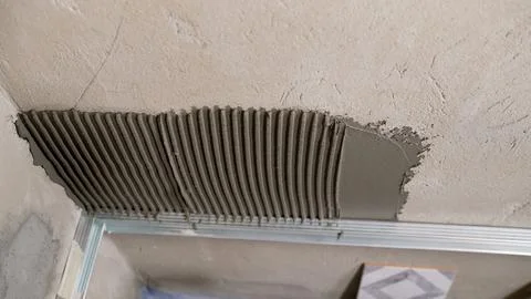 Applying glue to the wall with a spatula. Installation of a gypsum 3D panel.  Stock Photos