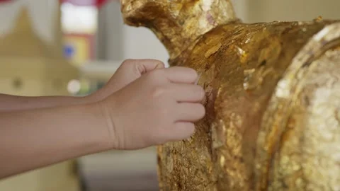 Applying gold leaf to Buddha statue making wishes for good fortune, representing Video stock 328492096