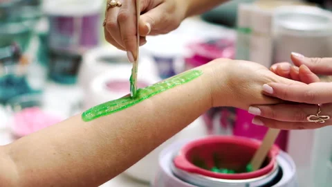Applying green paste for sugaring with a wooden stick to the female hand Stockbeeldmateriaal 257251300