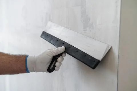 Applying joint compound with trowel on drywall surface in renovation project Stock Photos