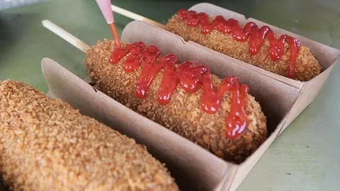 Applying ketchup on a Korean corn dog in a paper tray Stock Footage 331955953
