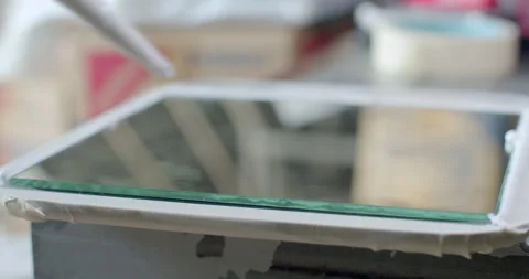 Applying a line of silicone glue to the mirror using a caulking gun. Stock Footage 312311902
