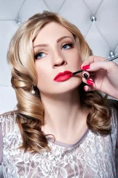 Applying lipstick on the lips by make-up brush Stock Photos