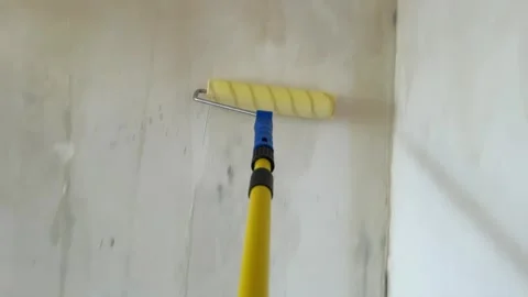 Applying liquid primer coat to wall with roller on extension pole Stock Footage 340403994