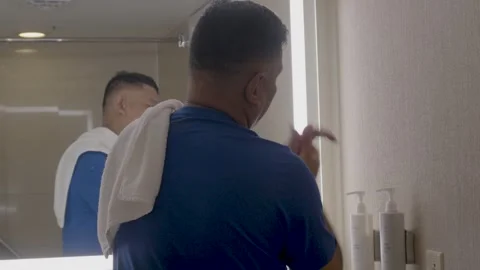 Applying lotion in front of bathroom mirror Video stock 320974990