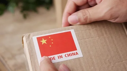 Applying MADE IN China flag label on a shipping box. Видео 306659709