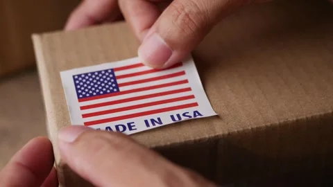 Applying MADE IN USA flag label on a shipping box. Stock Footage 306659723