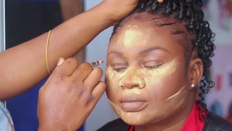 Applying makeup powder on face of an african woman	 Stock Footage 239589423
