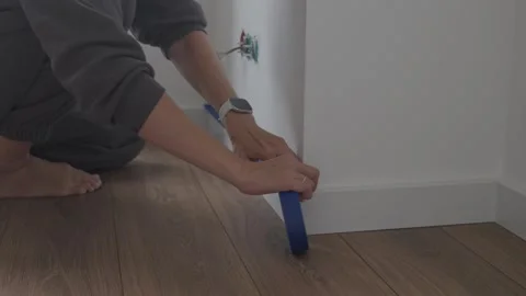 Applying masking tape on baseboard before wall painting Stock Footage 323679304