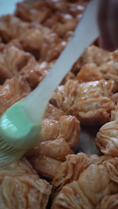 Applying melted butter to handmade pastries Stockbeeldmateriaal 345375686