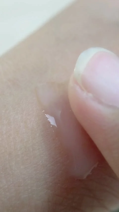 Applying milky white translucent beauty serum evenly on skin. Close up of m.. Stock Footage 336238707