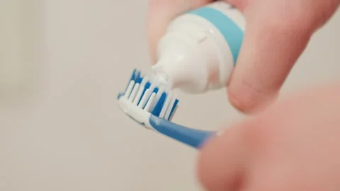 Applying minty toothpaste to toothbrush for routine. Closeup of hand squeezing Video stock 335633197