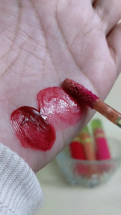 Applying nude or skin tone lip tint to palm using makeup brush. Vertical cl.. Stockbeeldmateriaal 338984773