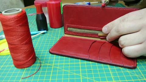 Applying paint to the edges red leather wallet DIY craft Stock-Footage 148049537